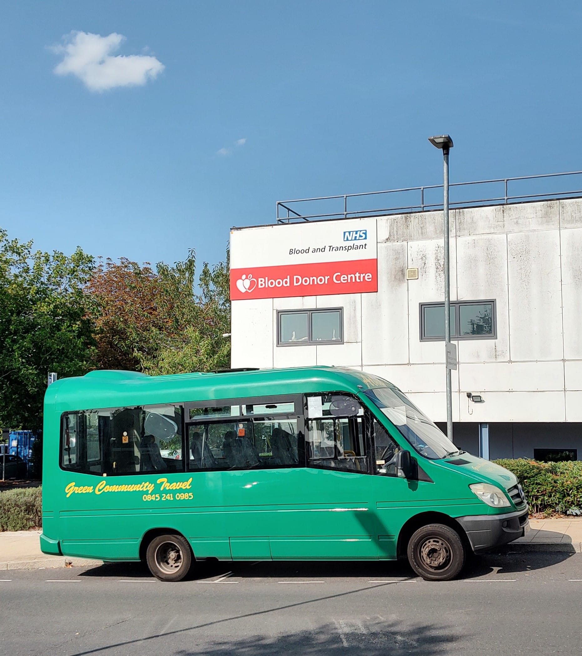 a green bus parked at a hospital